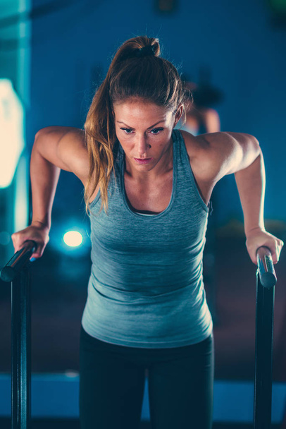 Atleta feminina em um ginásio exercitando-se em bares paralelos
  - Foto, Imagem