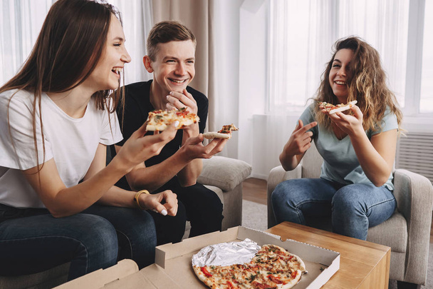 friends eating pizza and talking at home party - Foto, Imagen