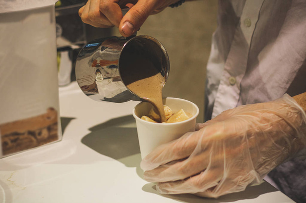Ein Mann bereitet Kakao zu, der Heißgetränk in Tassen mit weißen Marshmallows verschüttet. - Foto, Bild