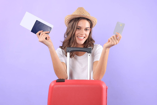 Tourist girl in showing plastic credit card with sunglasses, red suitcase, passport isolated on purple background. - Foto, afbeelding