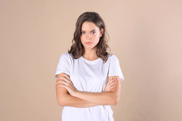 Cheerful brunette woman dressed in basic clothing looking at camera, isolated on beige background. - 写真・画像