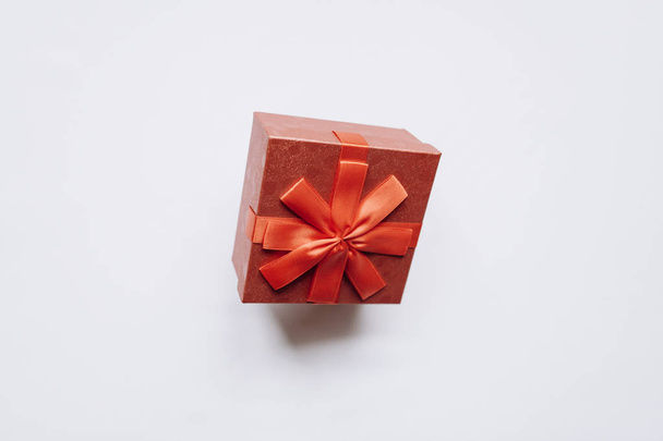 Caja roja con lazo con un regalo sobre fondo blanco
 - Foto, imagen