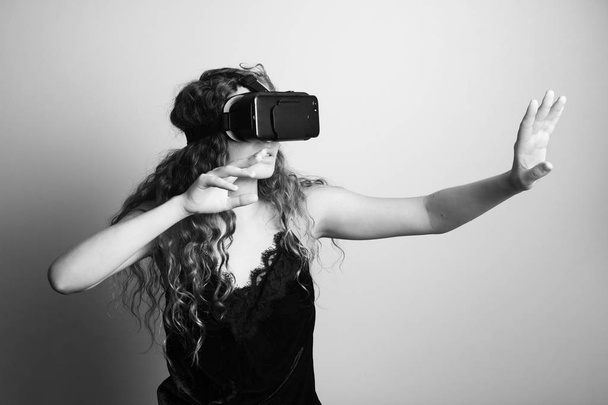 zwart-wit schot van mooie jonge vrouw met een vr headset reputatie voor witte muur - Foto, afbeelding