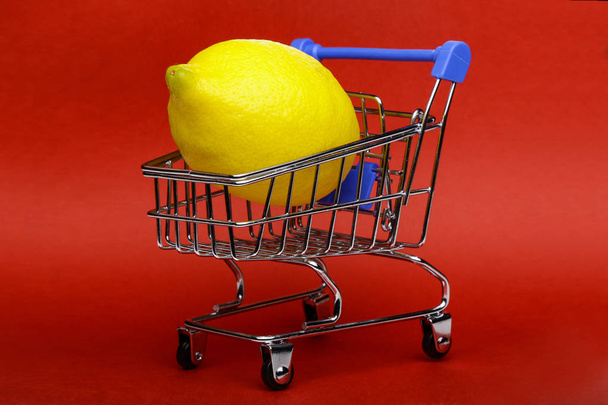 Lemon in shopping cart, shopping trolley on red background - Foto, Imagem