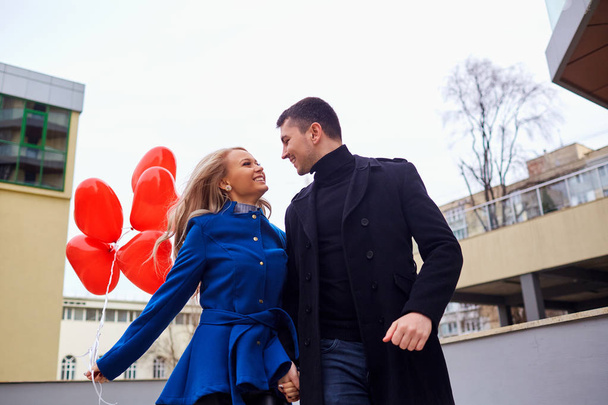 A loving couple in a coat with balloons hearts in hands on a cit - Foto, Bild