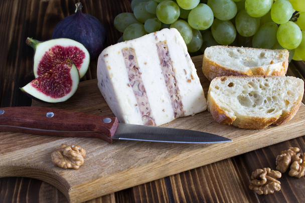 Zachte kaas met noten, brood en fruit op de houten snijplank - Foto, afbeelding