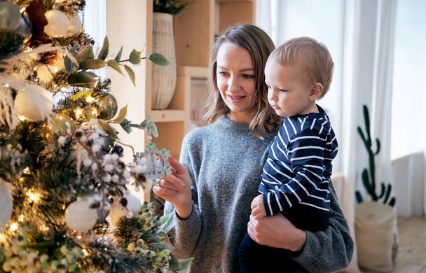 Mother and son wearing pajamas decorating Christmas tree - Photo, image