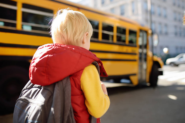 Pupil with schoolbag with yellow school bus on background. Back to school. - Foto, Imagen