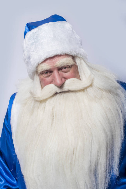 Santa Claus and Father Frost in a blue coat is standing against an isolated white background. An elder a patriarch and a wizard is looking at somebody or something. - Foto, immagini
