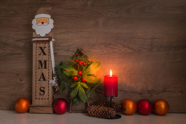 Різдвяні прикраси з палаючої червоний Свічка, дерев'яні Санта-Клауса, ялинку, дрібнички на столі, дерев'яні фон для тексту - Фото, зображення