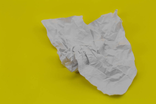 τσαλακωμένο φύλλο από λευκό χαρτί σε κίτρινο φόντο - Φωτογραφία, εικόνα