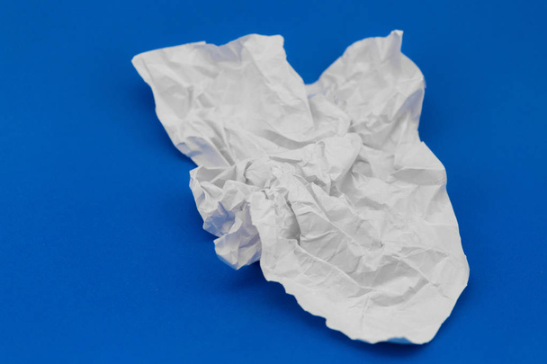τσαλακωμένο φύλλο από λευκό χαρτί σε μπλε φόντο - Φωτογραφία, εικόνα