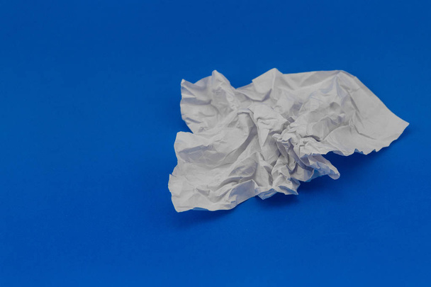 folha amassada de papel branco sobre fundo azul
 - Foto, Imagem