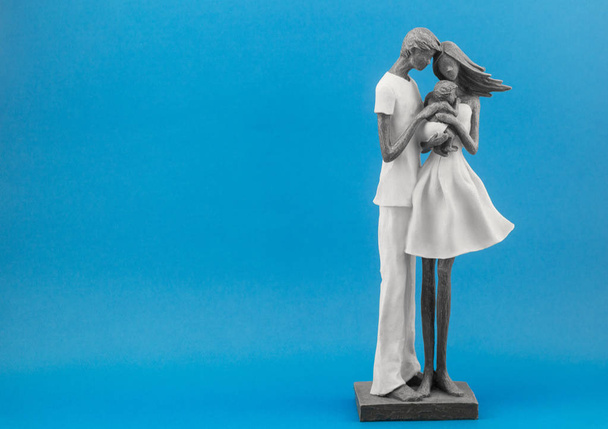 ceramic figure of father and mother holding a child. symbol of family and love - 写真・画像
