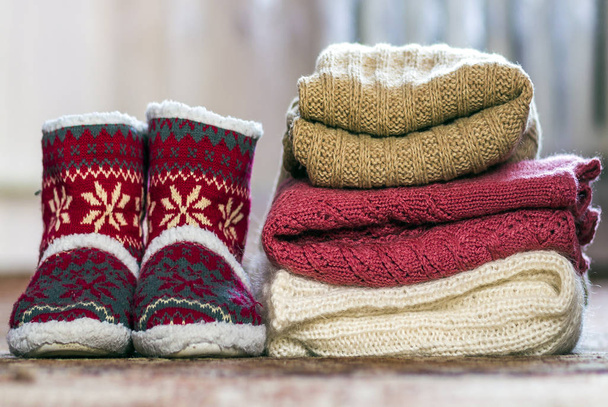 Zapatos rojos con patrón de año nuevo y una pila de suéteres de punto
 - Foto, Imagen