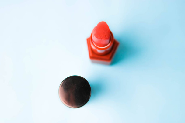 Caja de belleza, conjunto de cosméticos femeninos del lápiz labial rojo y resaltador sobre un fondo azul. Acostado. Vista superior
 - Foto, imagen
