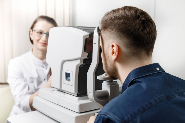 Vrouwelijke arts oogarts kliniek controleert oog visie van de mens op machine lamp. - Foto, afbeelding