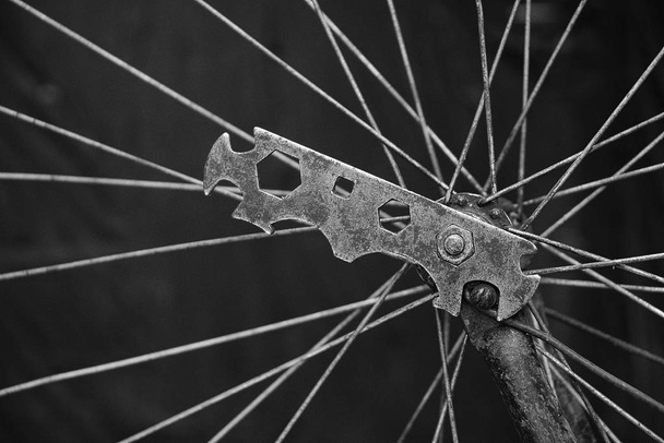 Herramienta de hierro vieja en una tuerca en una rueda de bicicleta con agujas de tejer
 - Foto, Imagen