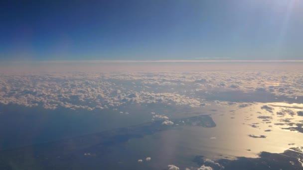 Beautiful aerial view of cloudscape from sky level, showing heaven-like scenery of clouds moving, both above and below in late afternoon pale pink lights from the right, and blue sky color on top - Footage, Video