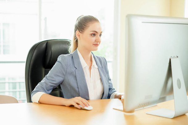 Beautiful business lady sitting at the table with laptop in office. - Фото, изображение