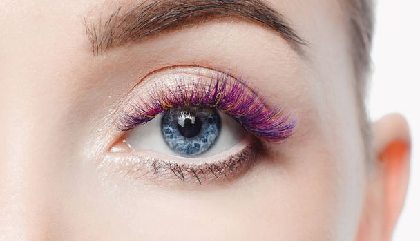 Eyelash extension procedure. Beautiful woman with long colored hairs lash in beauty spa salon. - Photo, Image