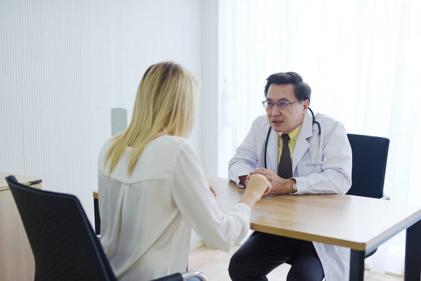 Doctor is talking with woman patient at table - Foto, afbeelding