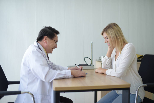 El doctor está hablando con una paciente en la mesa.
 - Foto, imagen