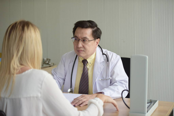 Ο γιατρός μιλάει με γυναίκα ασθενή στο τραπέζι. - Φωτογραφία, εικόνα