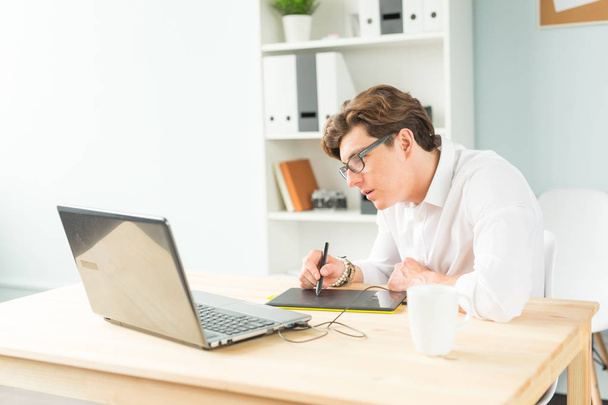 Бизнес, дизайн и концепция людей - симпатичный молодой человек в белой рубашке с графической табличкой на деревянном столе
 - Фото, изображение