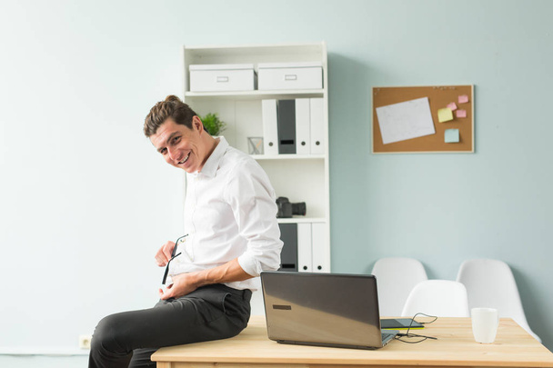 Concept affaires, humour et personnes - Jeune homme en chemise blanche assis sur une table en bois
 - Photo, image