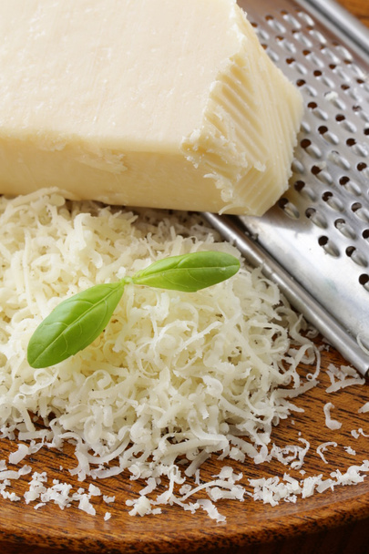 fromage parmesan râpé et râpe métallique sur plaque de bois
 - Photo, image