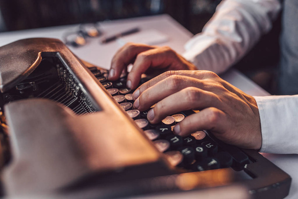Manos masculinas escribiendo en una máquina de escribir retro en el interior
 - Foto, Imagen