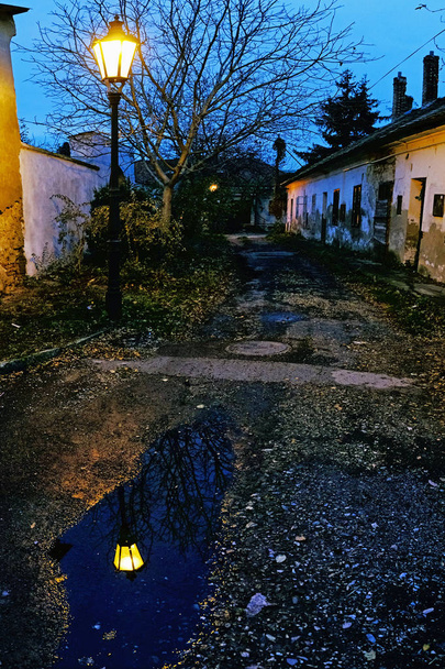 alte Häuser und Lichter mit Spiegelungen. Abendliche Straßenszene, Nitra, Slowakische Republik. - Foto, Bild