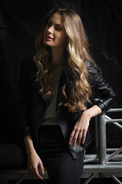 Beautiful girl with long curly hair in black leather jacket, t-shirt and jeans - Foto, imagen