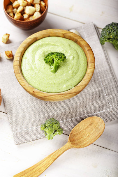 broccoli cream soup in a plate on a dark wooden background. next to the bowl of soup is a plate of breadcrumbs. top vie - Foto, Imagen