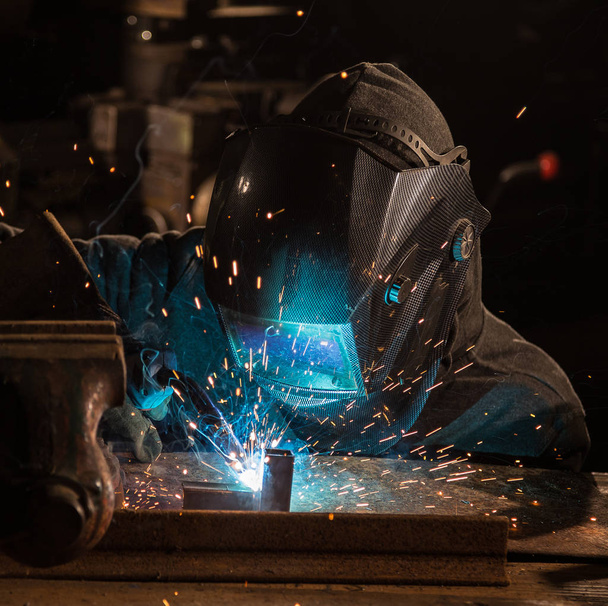 Welder is welding metal part in factory - Foto, Bild