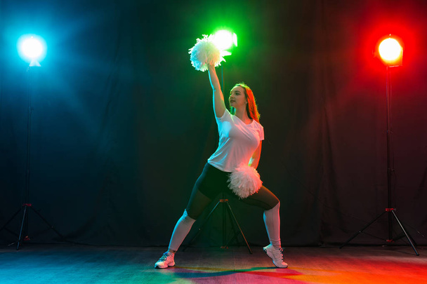 Cheerleading young woman dancing with pom-poms on colourful background - Photo, Image