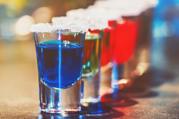 Alcoholic cocktail row on bar counter, colorful shooters cocktails drinks - Фото, изображение