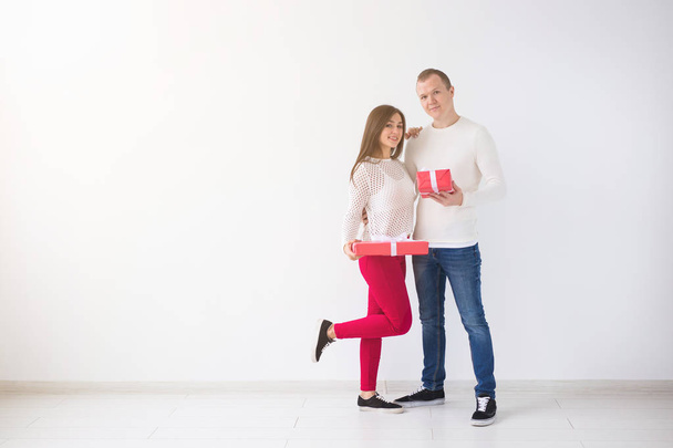 People, christmas, birthday, holidays and valentines day concept - happy young man and woman with gift boxes on white background with copy space - Fotoğraf, Görsel