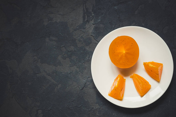 persimmonripe orange fruiton a dark rustic background texture and copy space - Photo, image