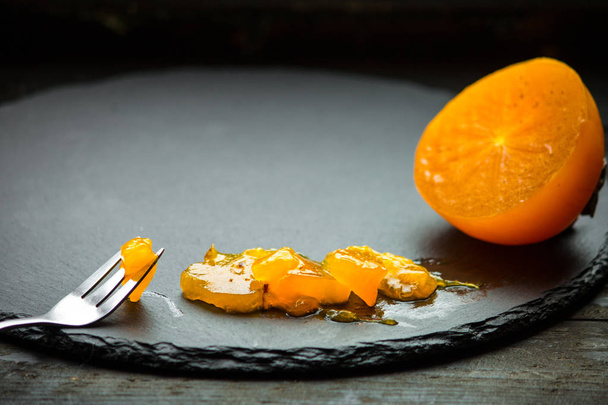 fruta naranja persimmonripe sobre un fondo rústico oscuro textura y espacio de copia
 - Foto, Imagen
