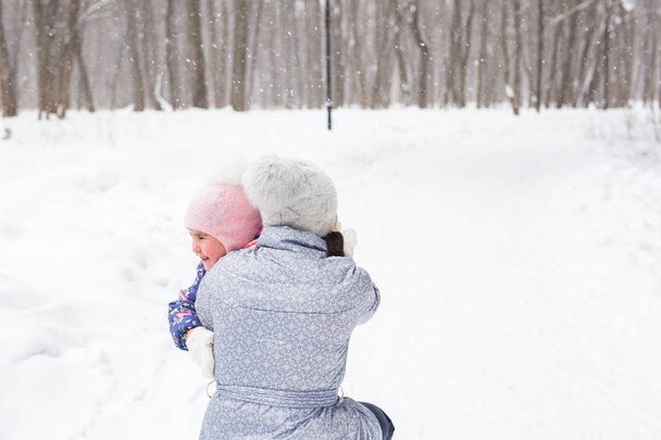 Perhe, lapset ja luonto konsepti - Äiti, jolla on tytär, pitää hauskaa talvipuistossa
 - Valokuva, kuva