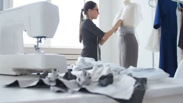 衣料品の設計と製作のコンセプトです。若い女性の裁縫師の服デザイナーの彼のスタジオで作業 - 映像、動画