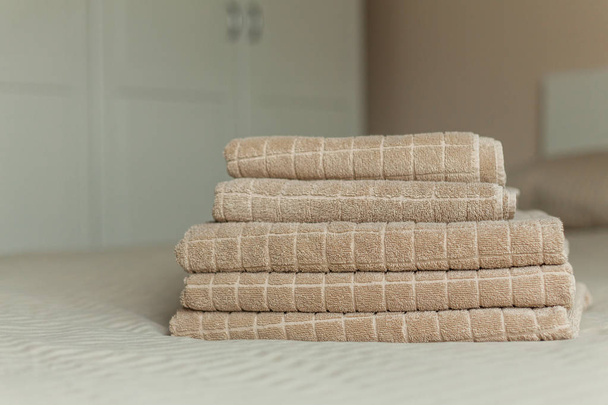 Stack of beige hotel towel on bed in bedroom interior. Soft focus. - Zdjęcie, obraz