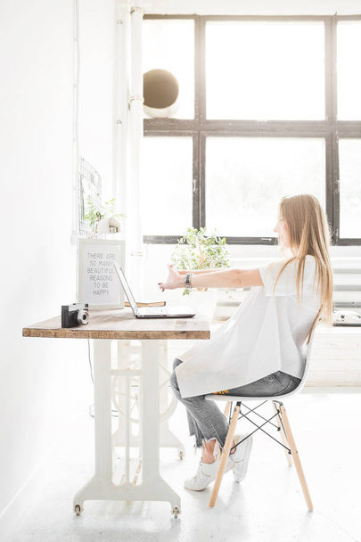 Young business woman working at home behind a laptop and stretching her hands. Creative Scandinavian style workspace - Foto, Imagem