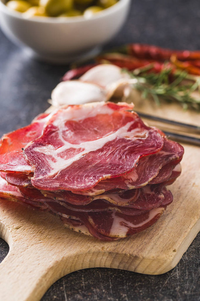 Dried pork meat slices on cutting board. - Foto, afbeelding