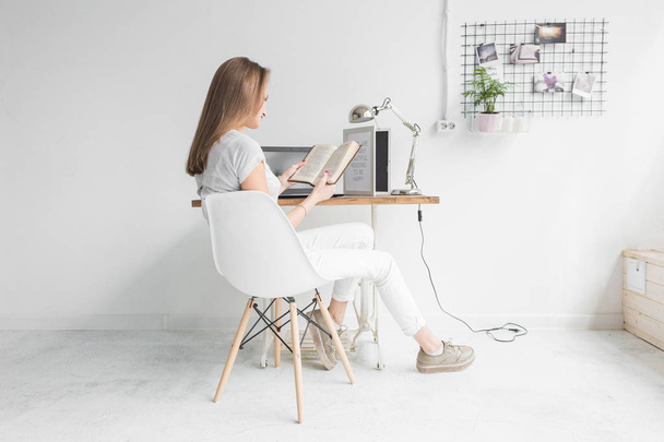 Young business woman working at home and reading a book. Creative Scandinavian style workspace - Fotoğraf, Görsel