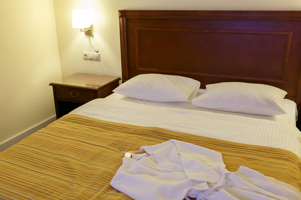 Roupão é mentira em uma grande cama de casal em um quarto de hotel
 - Foto, Imagem