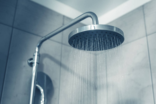 Wasser läuft aus dem Duschkopf im Badezimmer. Blautöniges Image - Foto, Bild