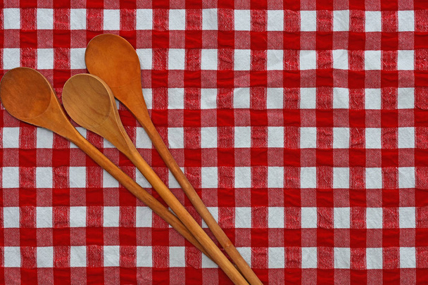 Immagine di tre cucchiai di legno mescolati su una tovaglia rossa a quadretti
.  - Foto, immagini